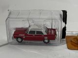 a red toy car in a clear box next to a candle