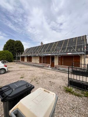 une voiture garée devant un immeuble dont le toit est équipé de panneaux solaires