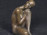 bronze statue of a man sitting on his knees with his hand on his chin