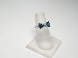 bague ornée de cristaux bleus et blancs, posée sur un support à bagues blanc