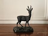 a statue of a deer standing on a wooden floor