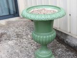 a green birdbath sitting on the sidewalk next to a building