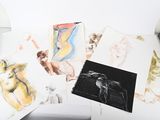a lot of drawings on a table with a lamp on it