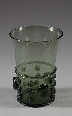 a green glass cup with a handle on a white table