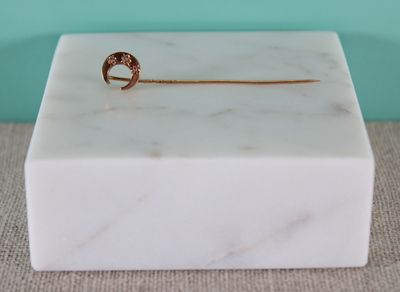 petit objet en marbre surmonté d'un anneau doré, sur fond bleu