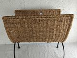 a wicker basket on a metal stand on a white surface