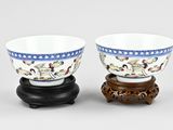 pair of chinese porcelain bowls on wooden stand on grey background