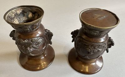 two metal vases sitting on a table with a white background