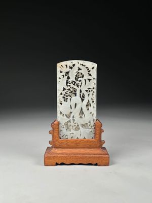 a white jade plaque on a wooden stand on a white surface