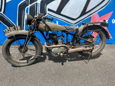 une vieille moto garée devant un mur recouvert de graffitis