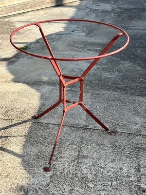 une table en métal rouge avec un plateau en verre, posée sur le trottoir