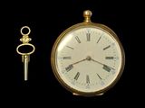 a gold clock and a key sitting next to each other
