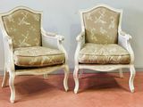 une paire de chaises peintes en blanc avec des coussins rembourrés beiges