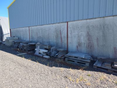 de nombreux objets métalliques anciens entassés à l'extérieur d'un bâtiment