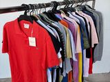 a lot of shirts hanging on a rack in a room