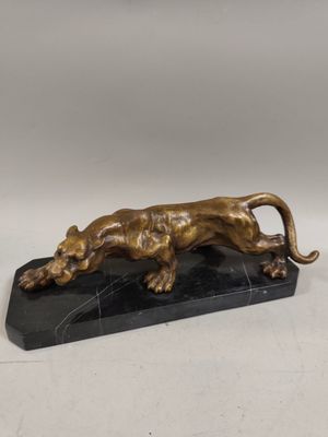 une statue en bronze représentant un lion, posée sur un socle en marbre