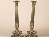 pair of antique brass candlesticks on a glass table