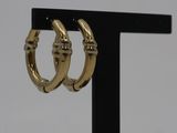 a close up of a pair of gold hoop earrings on a black stand