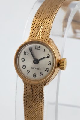 a gold wrist watch with a white dial on it