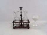 three glass vases on a wooden stand next to an hourglass