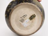 a hand holding a vase that has a label on it