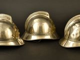 three silver fire helmets sitting on a black surface