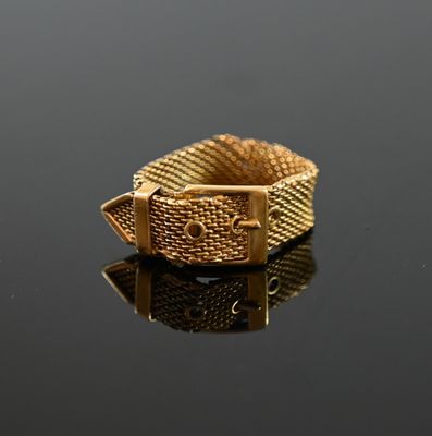 an image of a gold ring with a buckle on a black surface