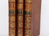 two old books sitting on top of each other on a white surface