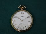 une montre de poche en or posée sur un tissu vert