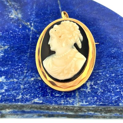 a close up of a picture of a woman ' s face in a gold plated pendant