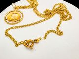 gold plated necklace with a coin and a chain on a white surface