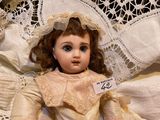 a doll that is sitting on a bed with a lace headband