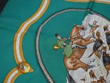 a green scarf with a picture of horses on it