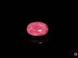 a close up of a pink stone on a black surface