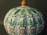 a white vase with a green and pink pattern on it