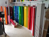 many rolls of colored paper on a shelf in a room