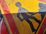 a yellow and red street sign on the side of the road
