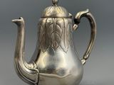 une théière ancienne en argent, avec une anse en forme d'oiseau, sur fond gris
