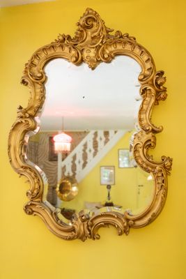 a mirror hanging on a yellow wall in a living room