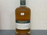 une bouteille de whisky posée sur une table à côté d'une bouteille de vin
