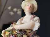 a figurine of a woman holding a basket of flowers