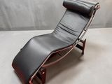 une chaise longue en cuir noir avec un piètement en bois