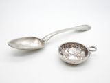une cuillère en argent et une cuillère en argent posées sur une surface blanche