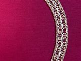 a close up of a necklace on a pink surface with a pink background