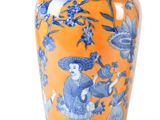 an orange vase with a blue and white design on it