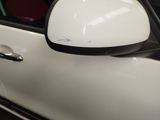 a side view mirror on a white car with a black trim