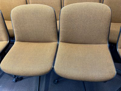 Plusieurs chaises sont alignées en rang dans une pièce vide.