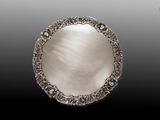 une assiette en argent antique avec un motif décoratif sur le bord