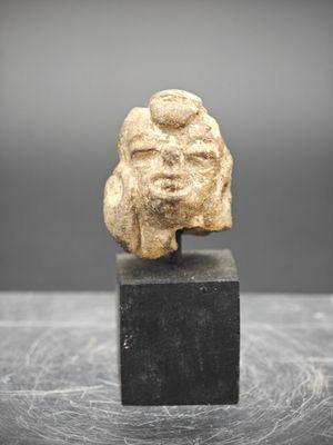 une ancienne tête d'homme sculptée dans la pierre, posée sur un socle