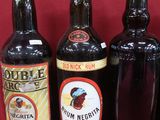 Plusieurs bouteilles d'alcool sont alignées sur une surface rouge